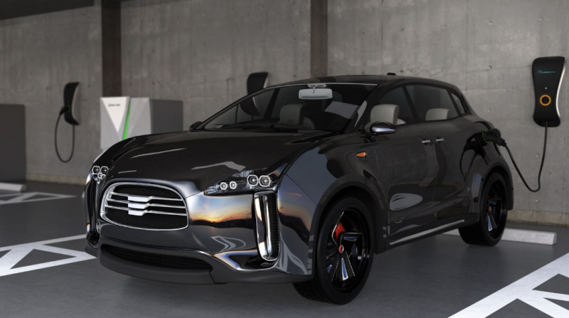 黑色電動車停在地下停車場的充電樁前進行充電，車身側面反射出夕陽的餘輝